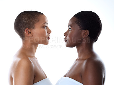 Buy stock photo Studio shot of two beautiful young women looking into each other's eyes while standing against a white background