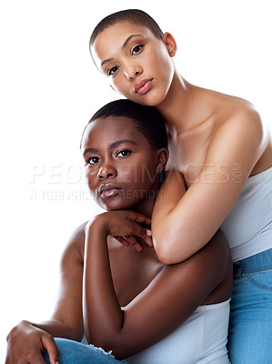 Buy stock photo Portrait of two beautiful young women holding each other while standing against a white background