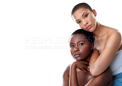 Buy stock photo Portrait of two beautiful young women holding each other while standing against a white background