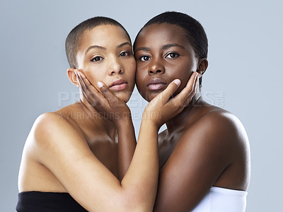 Buy stock photo Portrait shot of two beautiful young women holding each other's face while standing against a grey background