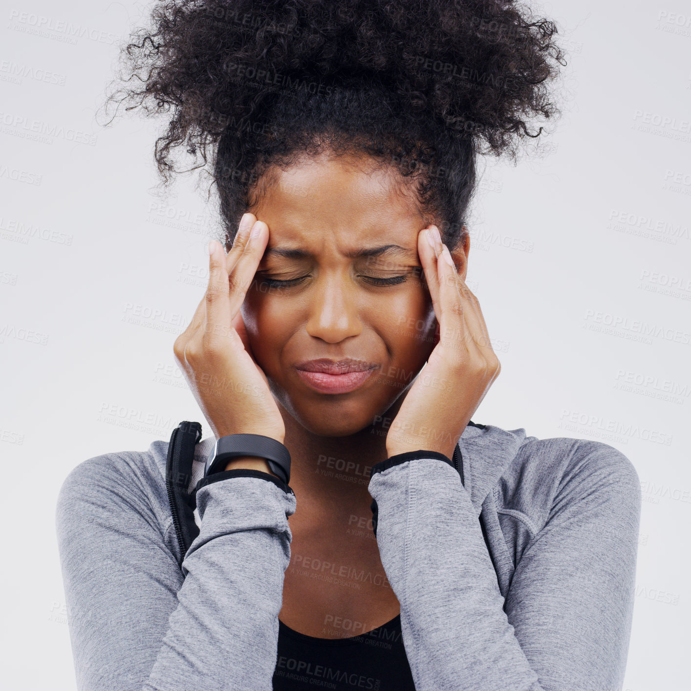 Buy stock photo Shot of a young woman holding her head while suffering from a headache against a grey background