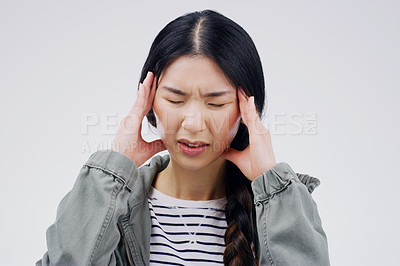 Buy stock photo Shot of a young woman holding her head while suffering from a headache against a grey background