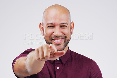 Buy stock photo Portrait of a handsome young man pointing towards the camera against a grey background