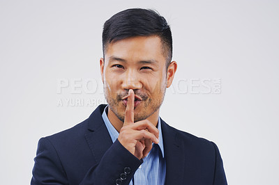 Buy stock photo Portrait of a handsome businessman posing with his finger on his lips against a grey background