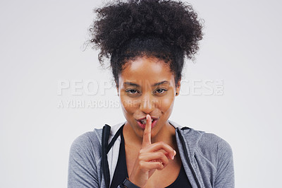 Buy stock photo Portrait of an attractive young woman posing with her finger on her lips against a grey background