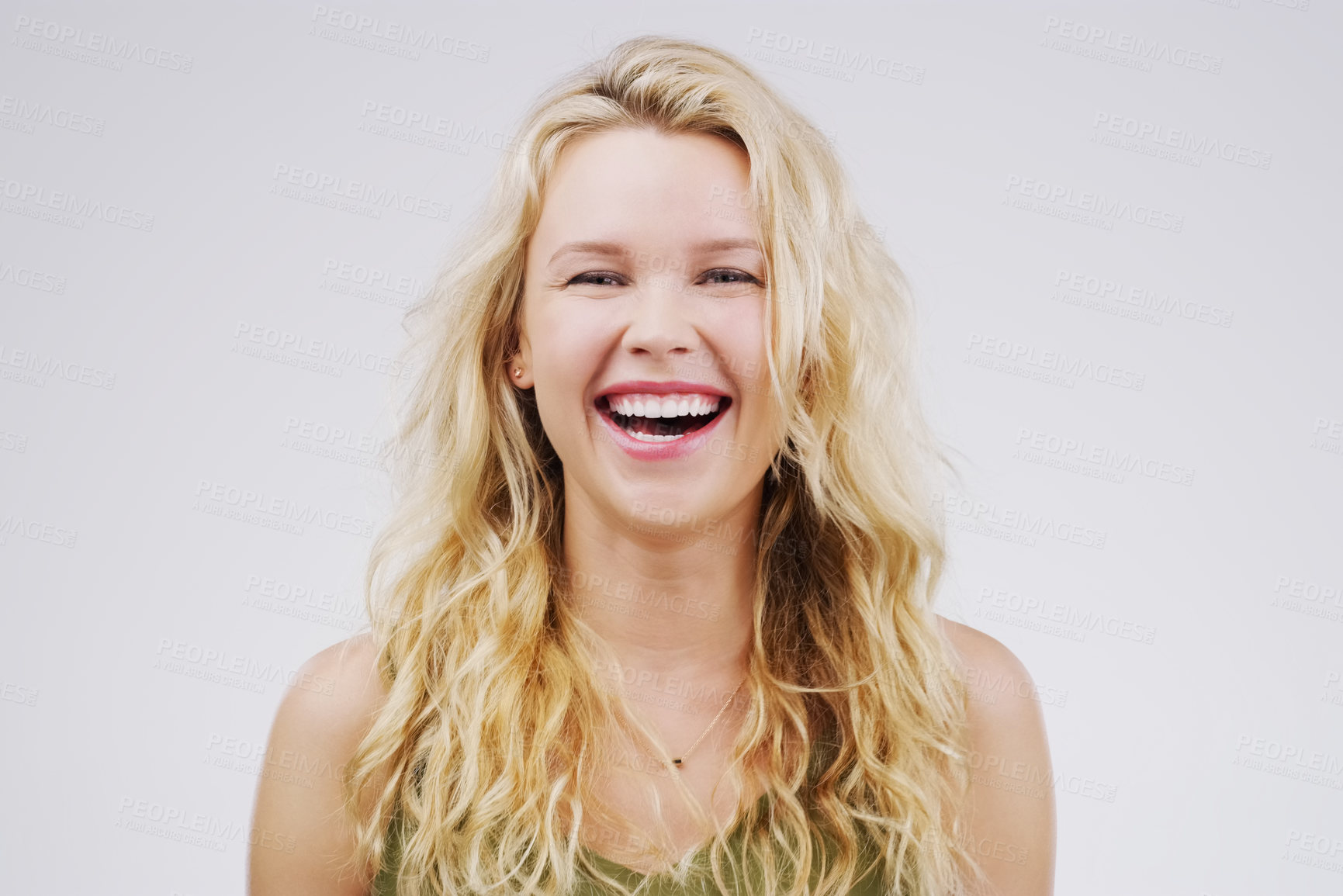 Buy stock photo Studio portrait of an attractive young woman laughing while standing against a grey background