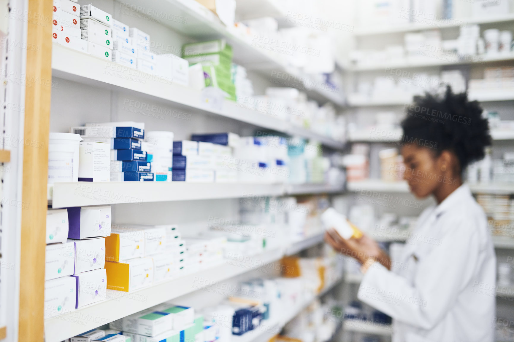 Buy stock photo Defocused shot of medication on shelves with a pharmacist in the background