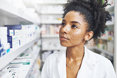 Buy stock photo Shot of a female pharmacist looking at the shelves in a chemist