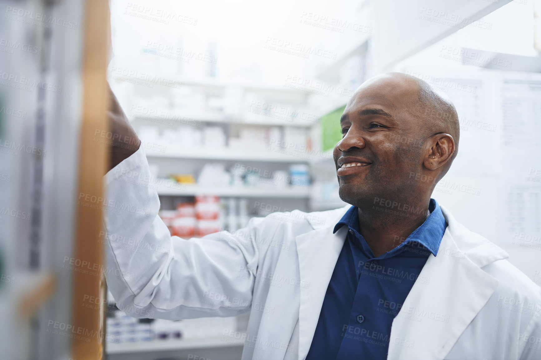 Buy stock photo Shot of a pharmacist looking for something on the shelves