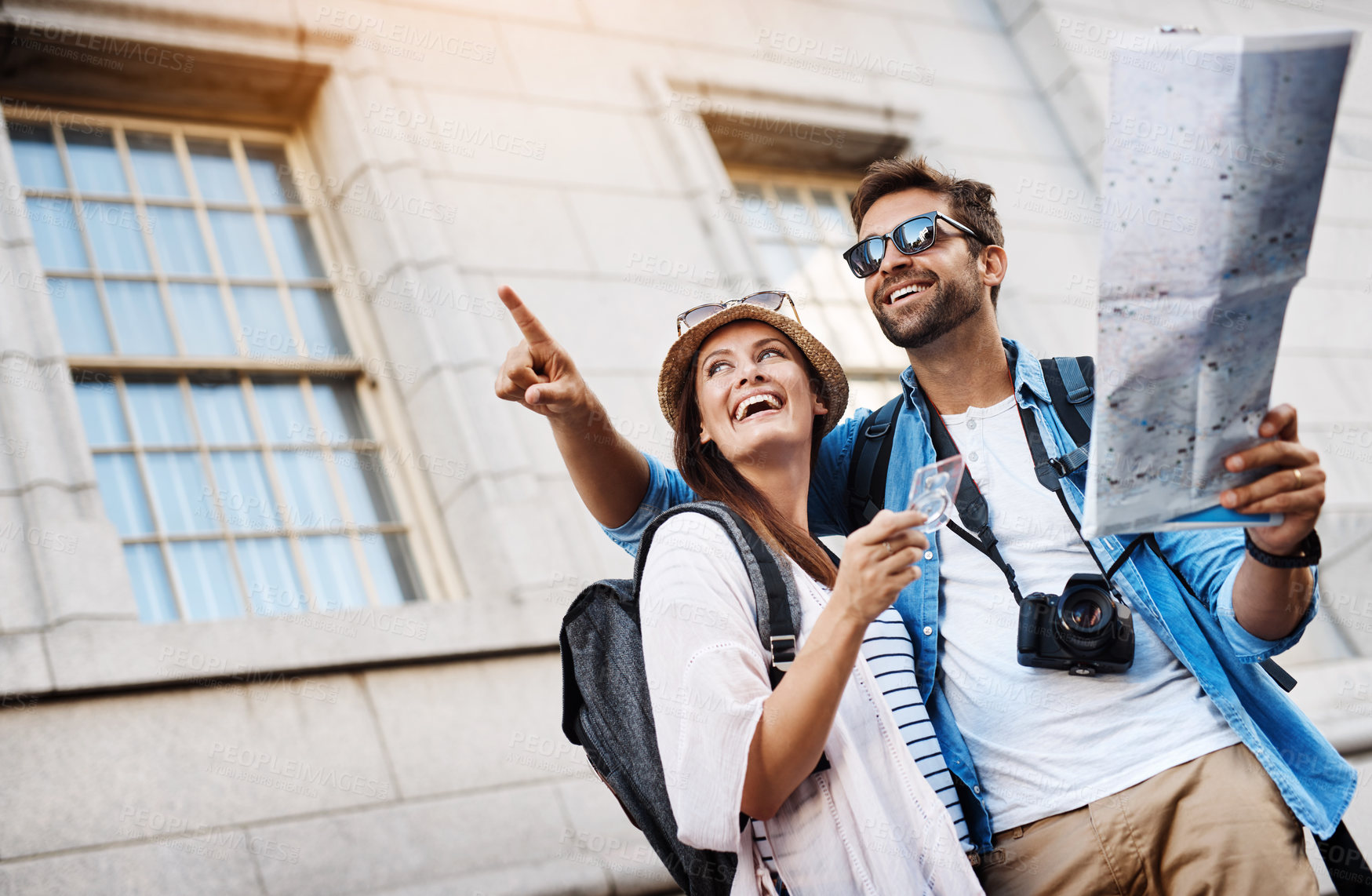 Buy stock photo Cropped shot of an affectionate young couple using a map while exploring a foreign city