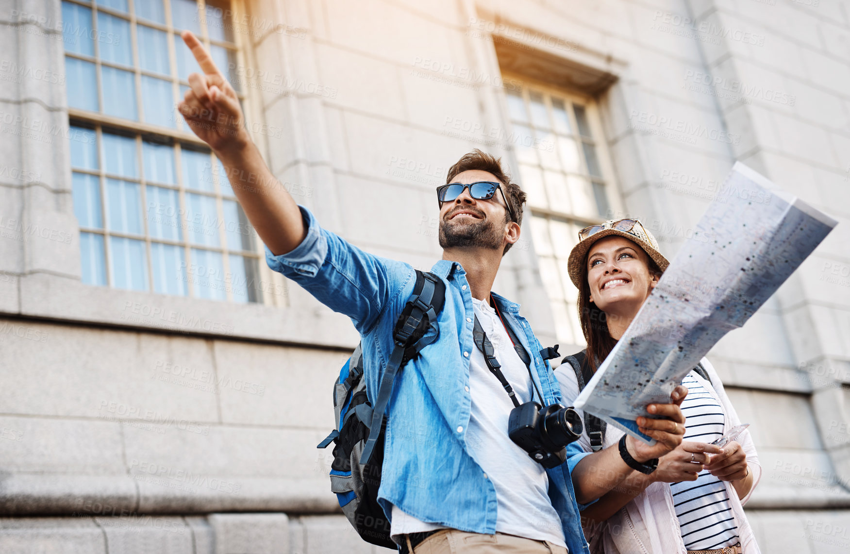 Buy stock photo Cropped shot of an affectionate young couple using a map while exploring a foreign city