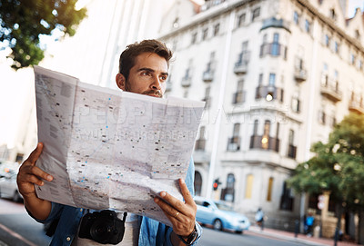 Buy stock photo Cropped shot of a handsome young man looking at a map while touring a foreign city