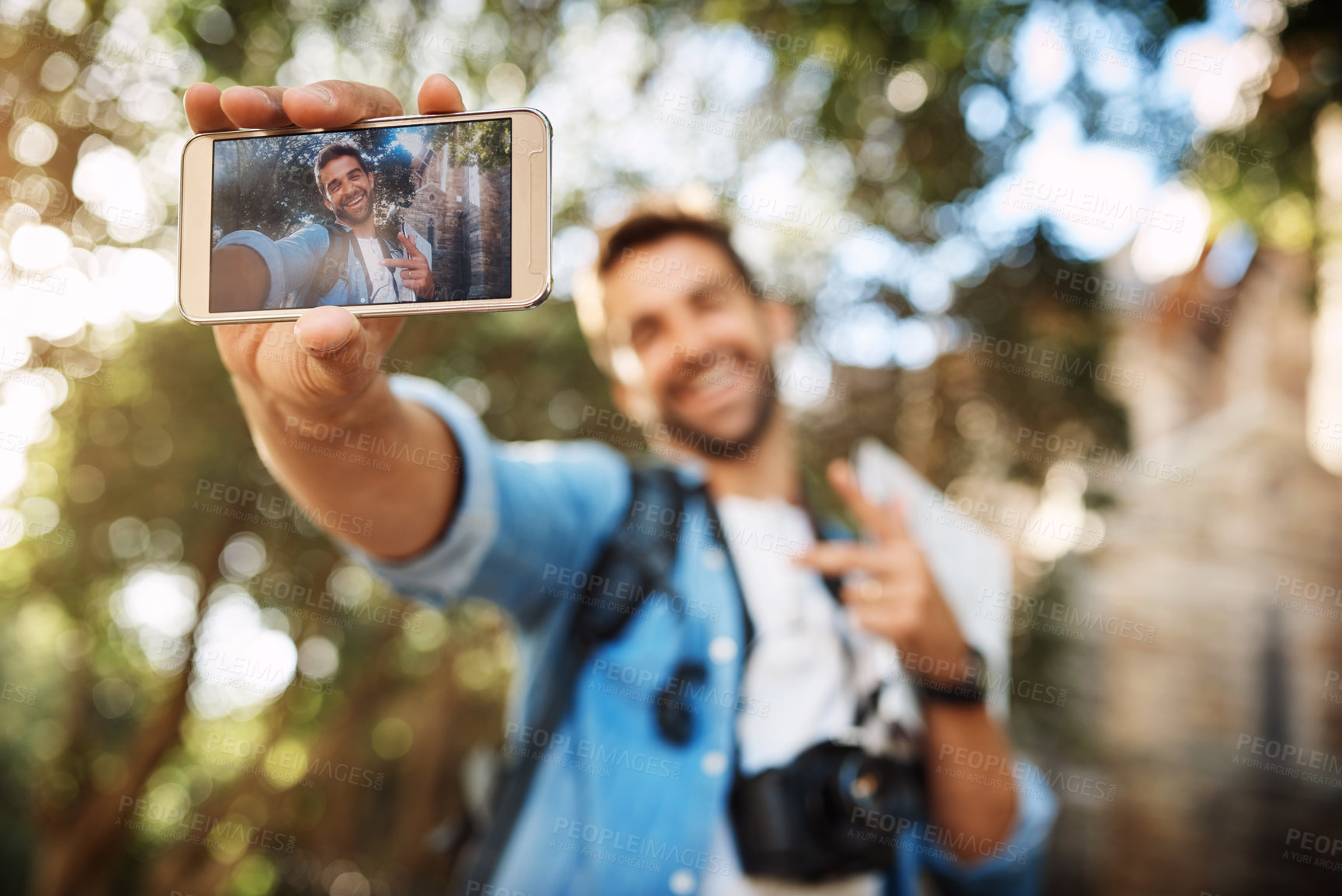 Buy stock photo Cropped shot of a handsome young man taking selfies on his mobile phone while on vacation