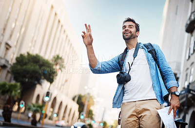 Buy stock photo Cropped shot of a handsome young man hailing a cab while exploring a foreign city