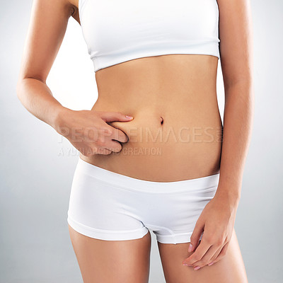 Buy stock photo Studio shot of an unrecognizable woman holding fat on her stomach against a grey background