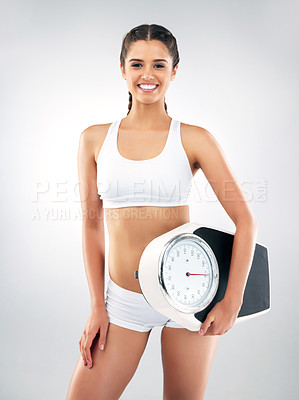 Buy stock photo Studio portrait of a beautiful and fit young woman holding a weight scale against a grey background