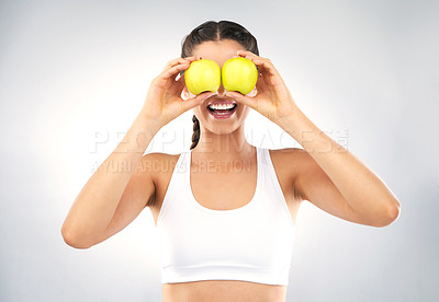 Buy stock photo Studio shot of a healthy young woman holding up apples in front of her eyes against a grey background