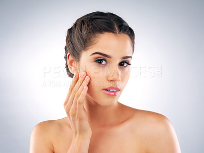 Buy stock photo Studio shot of a beautiful young woman with gorgeous skin touching her face against a grey background
