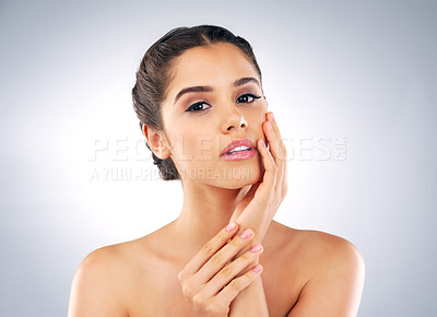 Buy stock photo Studio portrait of a beautiful young woman with gorgeous skin holding her face against a grey background