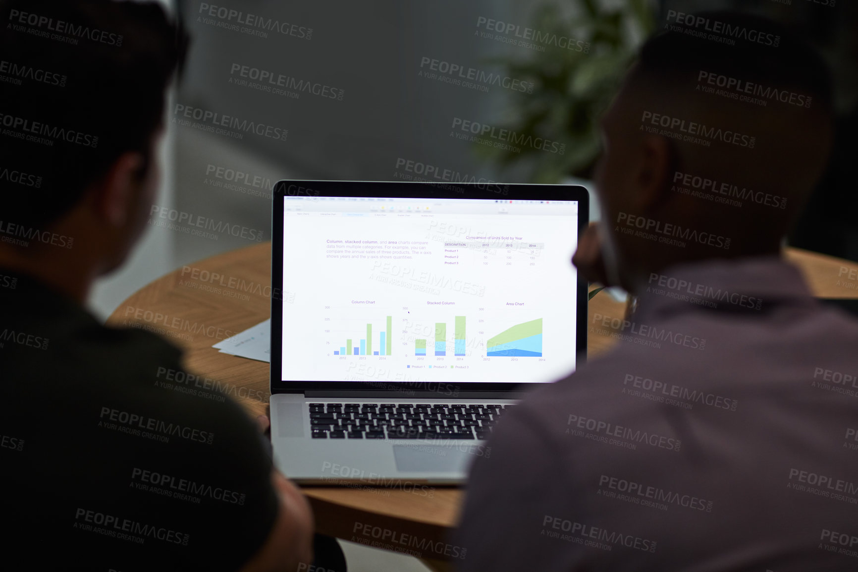 Buy stock photo Shot of two young businessmen using a laptop with graphs on the screen during a meeting in a modern office