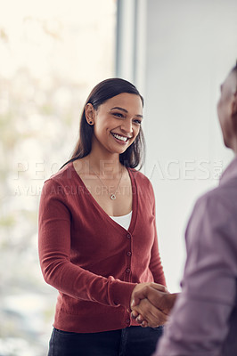 Buy stock photo Shot of a young businesswoman and businessman shaking hands in a modern office