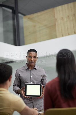 Buy stock photo Shot of a young businessman using a digital tablet during a meeting with colleagues in a modern office