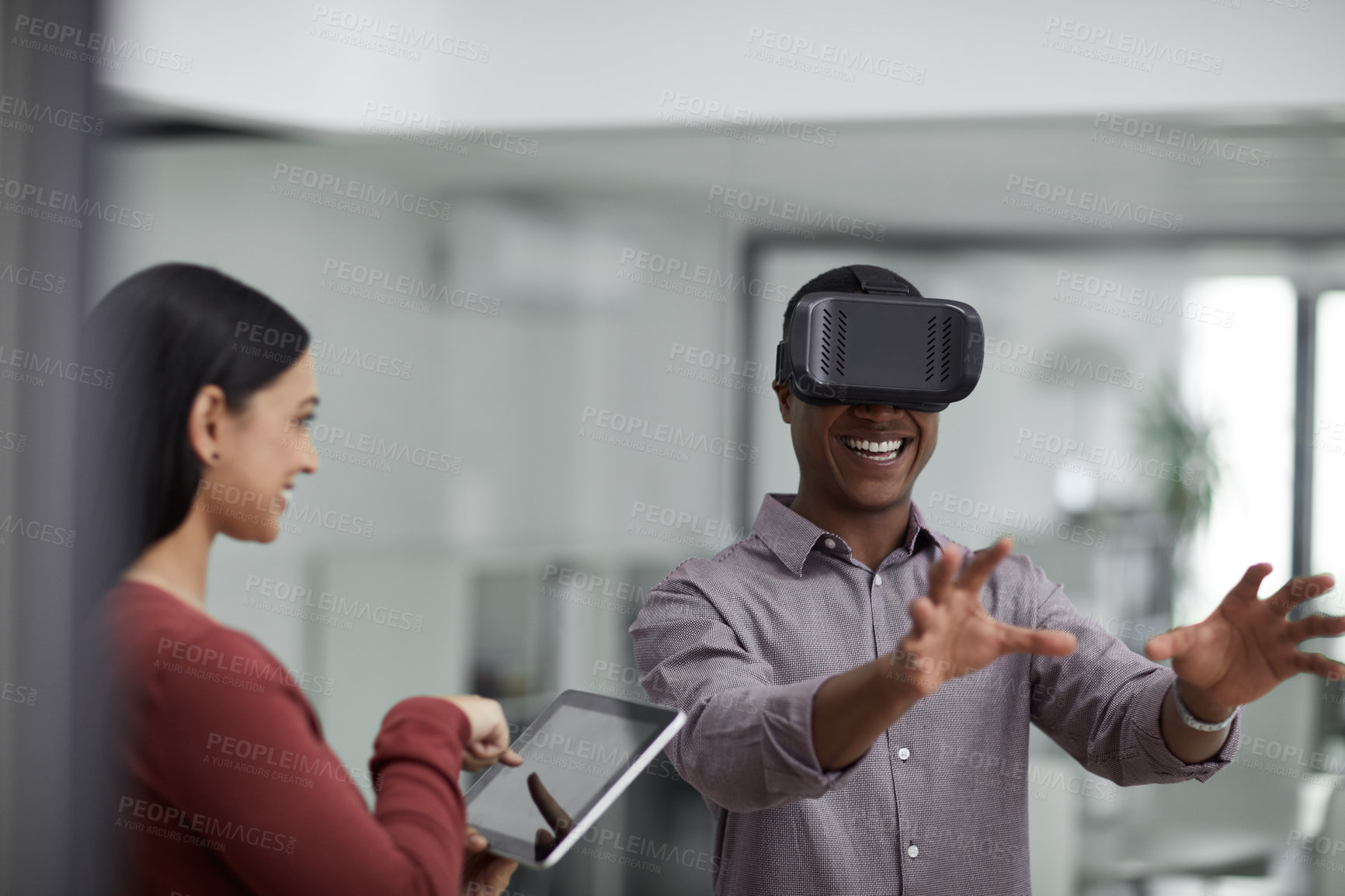 Buy stock photo Shot of two young colleagues using a digital tablet and a virtual reality headset in a modern office