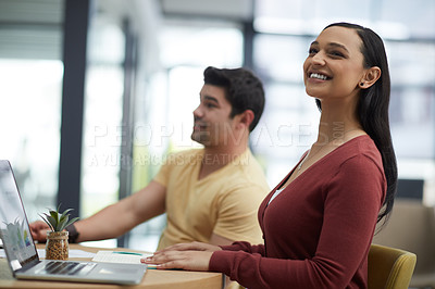 Buy stock photo Shot of a young businesswoman using a laptop with her colleague in the background