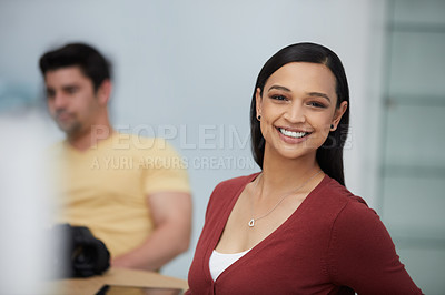 Buy stock photo Shot of a confident young businesswoman working a modern office with her colleague in the background
