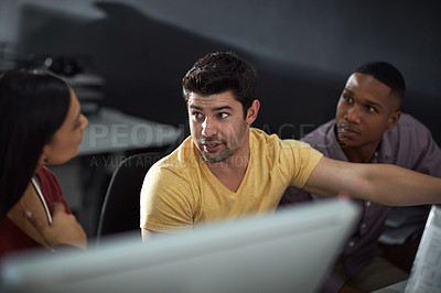 Buy stock photo Shot of a group of young businesspeople using a computer during a late night at work