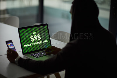 Buy stock photo Shot of an unrecognisable hacker using a laptop and smartphone