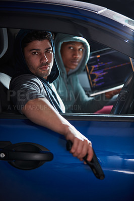 Buy stock photo Shot of two armed young hackers using a laptop in a car