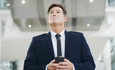 Buy stock photo Cropped shot of a mature businessman using a smartphone while walking through a modern office