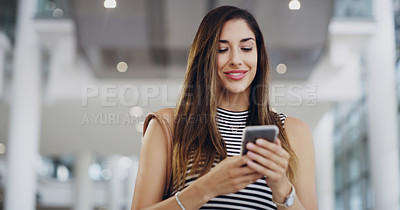 Buy stock photo Cropped shot of a young businesswoman using a smartphone while walking through a modern office