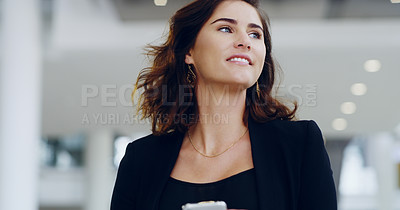 Buy stock photo Cropped shot of a confident young businesswoman using her cellphone while walking through a modern office