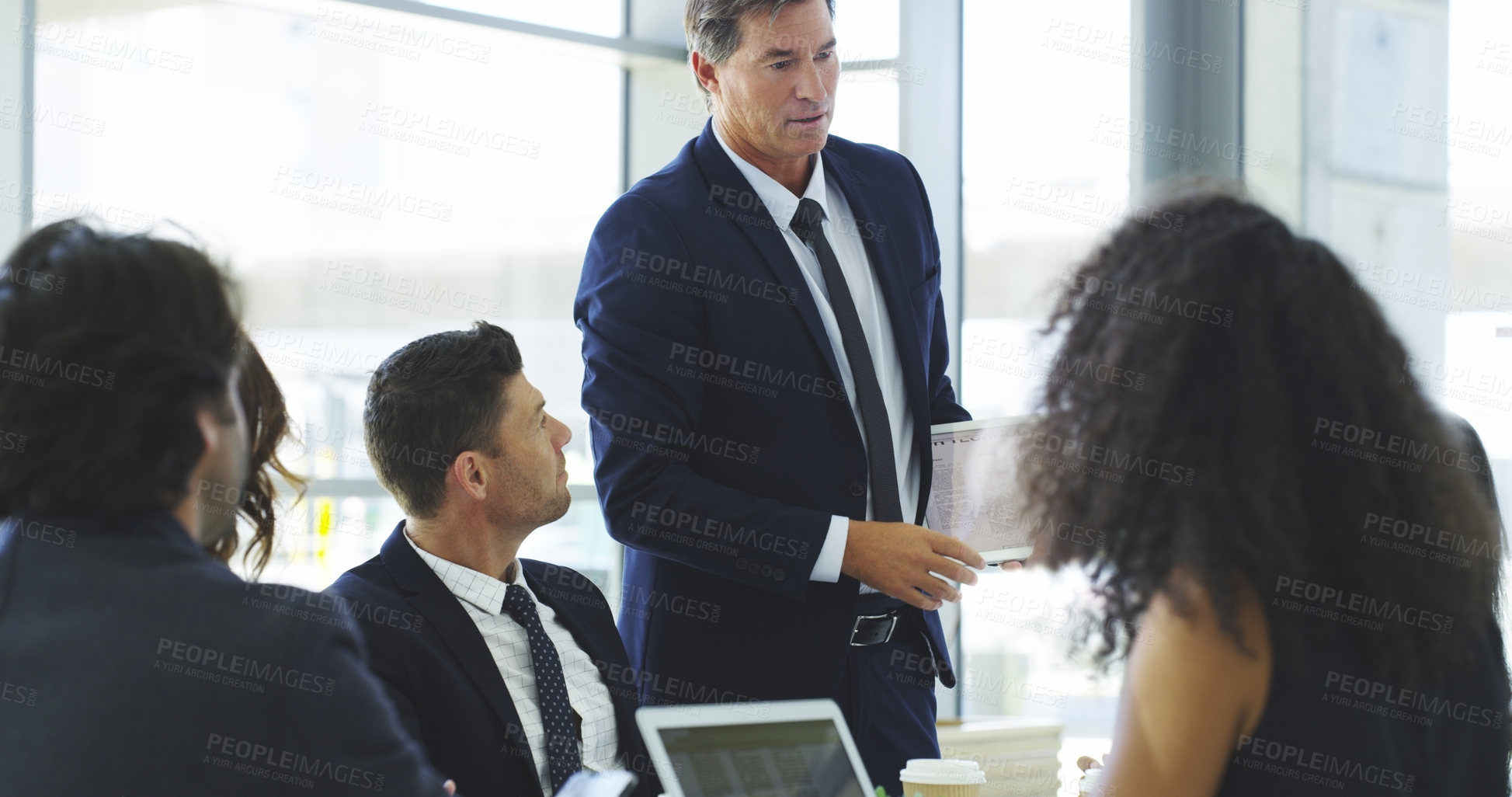 Buy stock photo Cropped shot of a businessman using a digital tablet while giving a presentation to his colleagues in an office