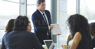 Buy stock photo Cropped shot of a businessman using a digital tablet while giving a presentation to his colleagues in an office