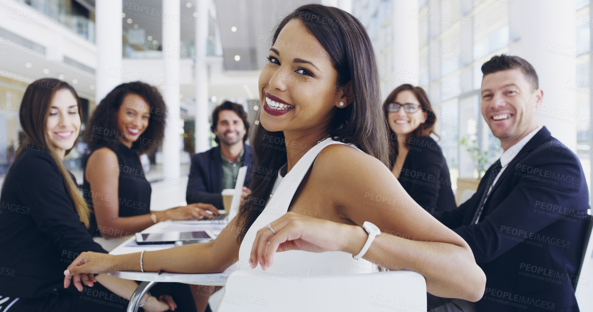 Buy stock photo Cropped shot of a young businesswoman smiling in an office during a meeting with her colleagues in the background