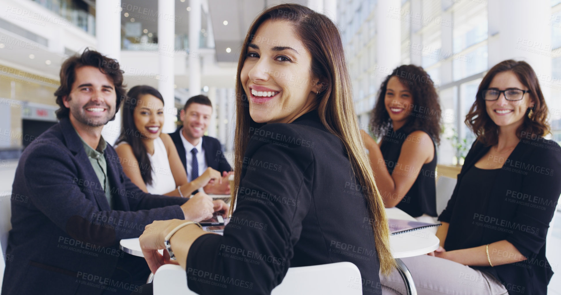 Buy stock photo Cropped shot of a young businesswoman smiling in an office during a meeting with her colleagues in the background