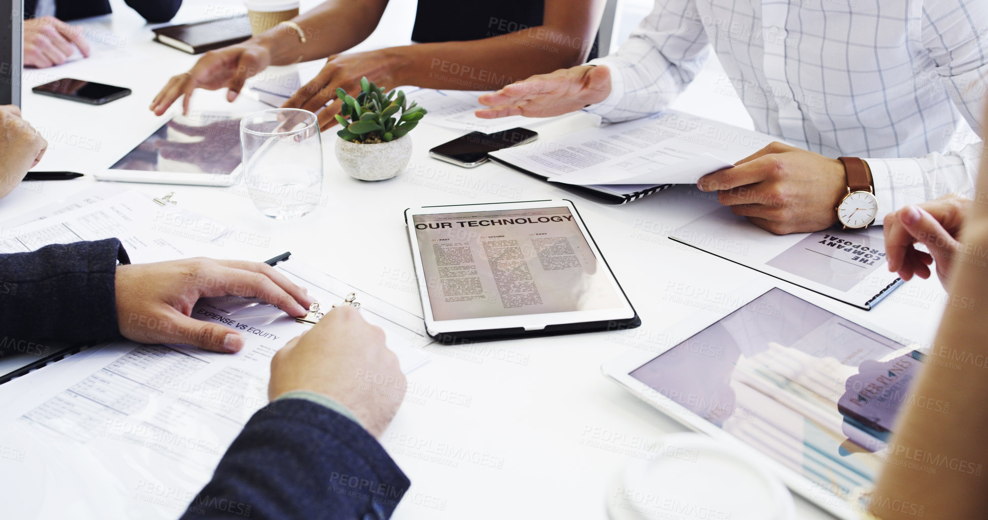 Buy stock photo Cropped shot of a group of businesspeople sitting around the boardroom table during a meeting