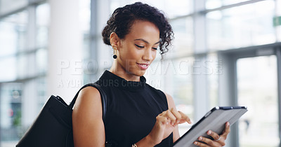 Buy stock photo Cropped shot of a young businesswoman using a digital tablet while walking through a modern office