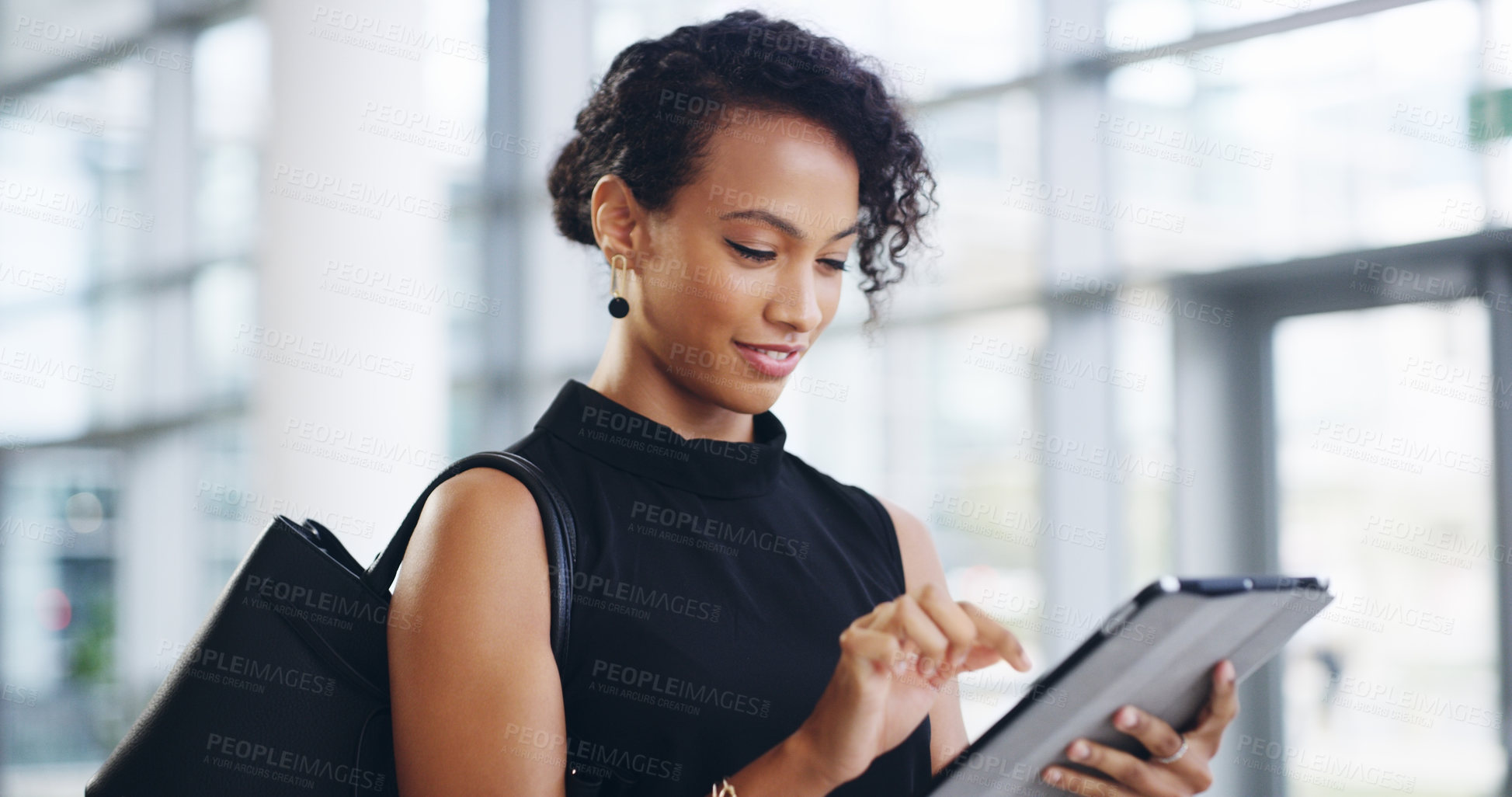 Buy stock photo Cropped shot of a young businesswoman using a digital tablet while walking through a modern office