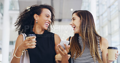 Buy stock photo Cropped shot of two young businesswomen chatting and using a smartphone while walking in an office on a coffee break