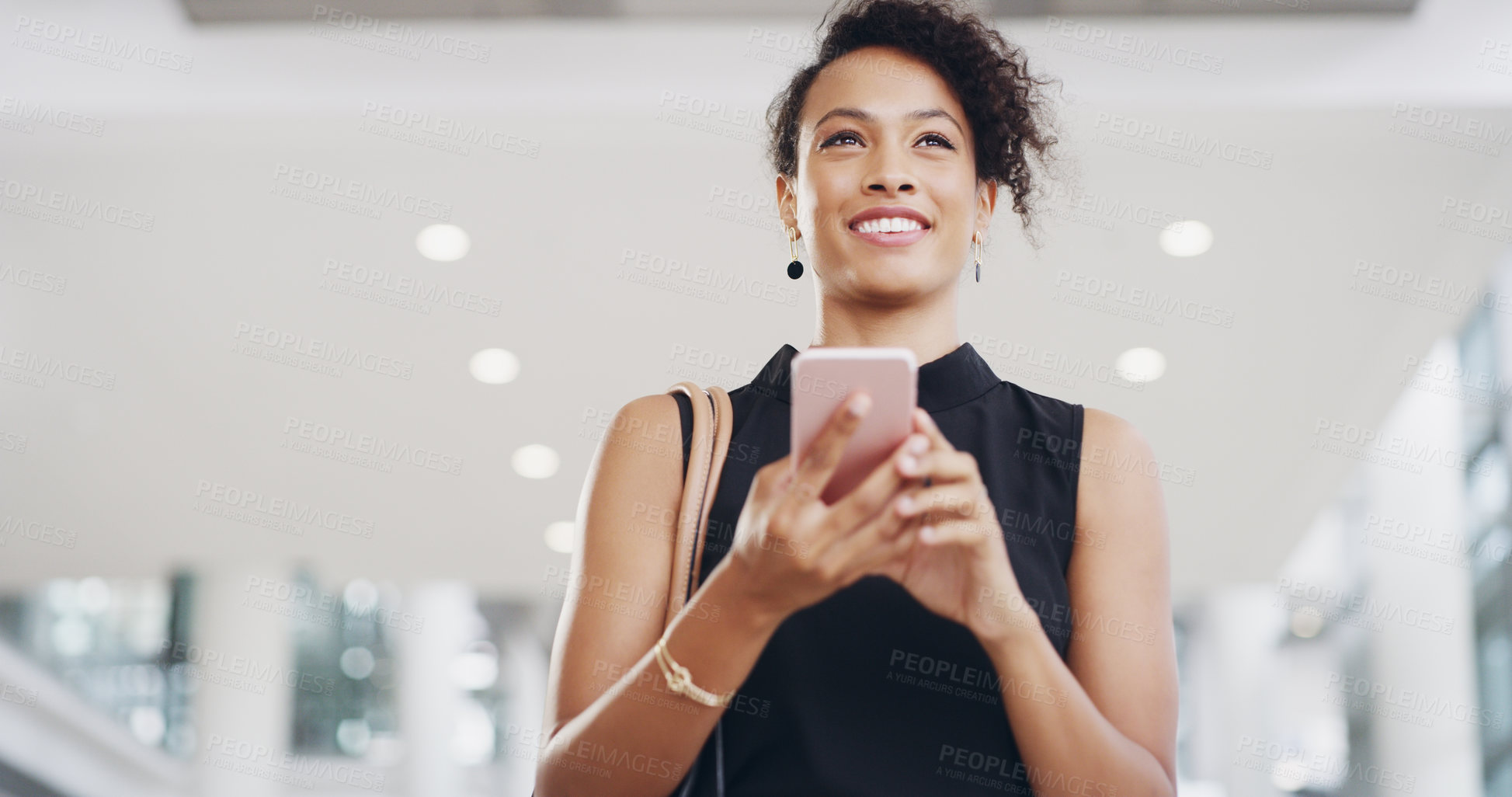 Buy stock photo Cropped shot of a young businesswoman using a smartphone and waving while walking through a modern office
