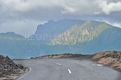 Buy stock photo Empty country road overlooking the mountains with cloudy sky copy space. A curved scenic road or asphalt roadway for traveling on a mountain pass in La Palma, Canary Islands, Spain