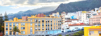 Buy stock photo Scenic landscape view of vibrant houses, traditional residential buildings or city structures. Tourism destination street on Santa Cruz road, La Palma, Spain with background mountains and cloudy sky