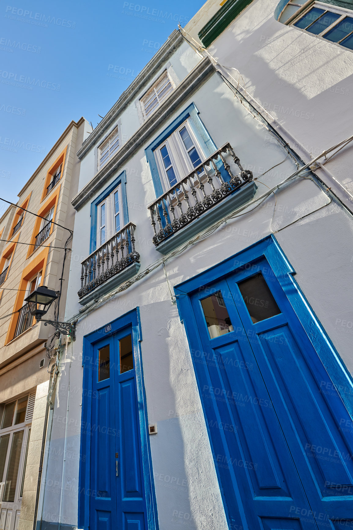 Buy stock photo Classic architecture of vibrant buildings with blue doors in a city. Low angle of ancient and traditional homes or houses in a small vintage town or village with bright colors and a unique design