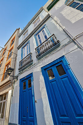 Buy stock photo Classic architecture of vibrant buildings with blue doors in a city. Low angle of ancient and traditional homes or houses in a small vintage town or village with bright colors and a unique design