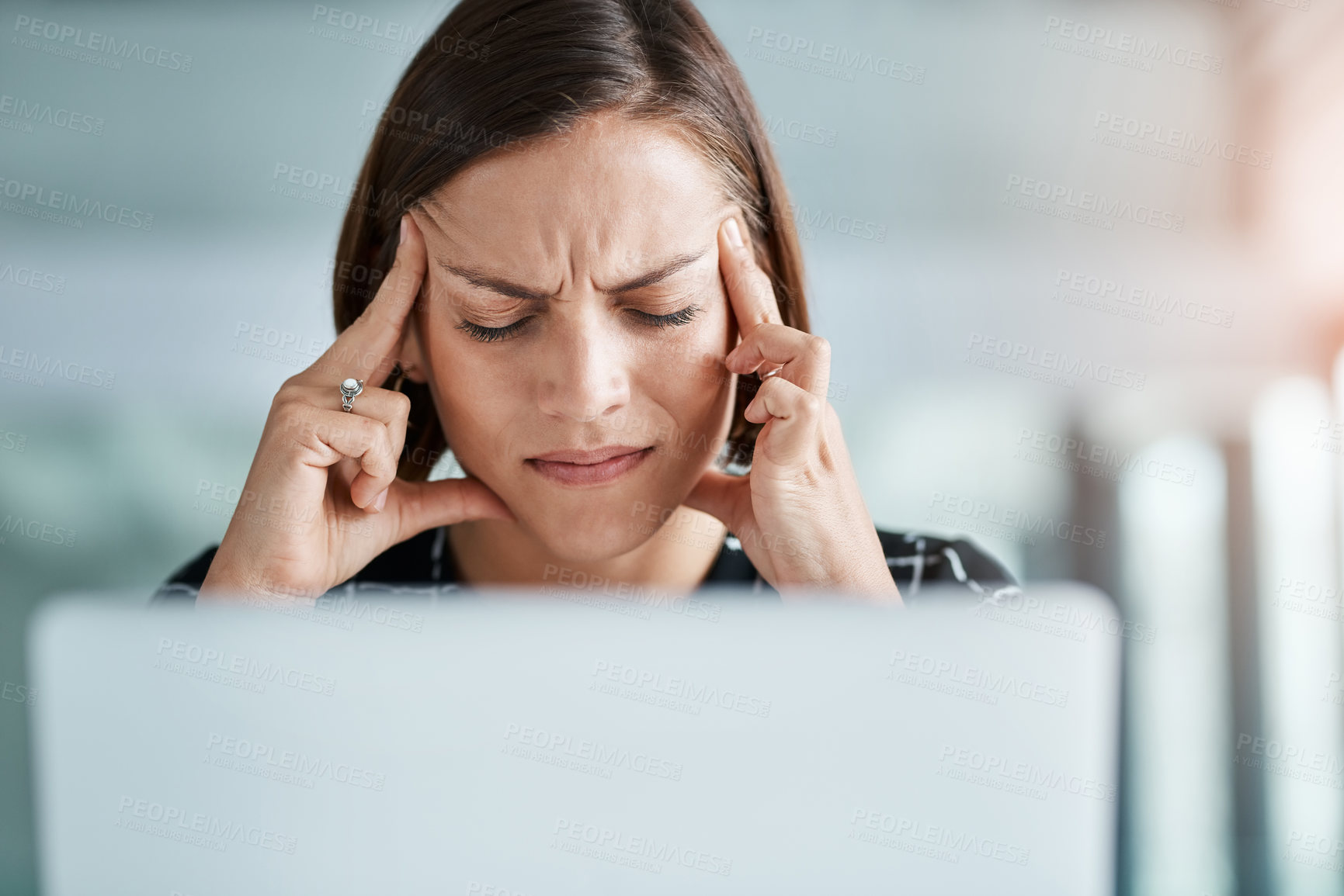 Buy stock photo Cropped shot of a young businesswoman suffering with a headache while working in an office