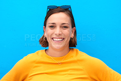 Buy stock photo Cropped portrait of a happy young woman smiling against a blue background